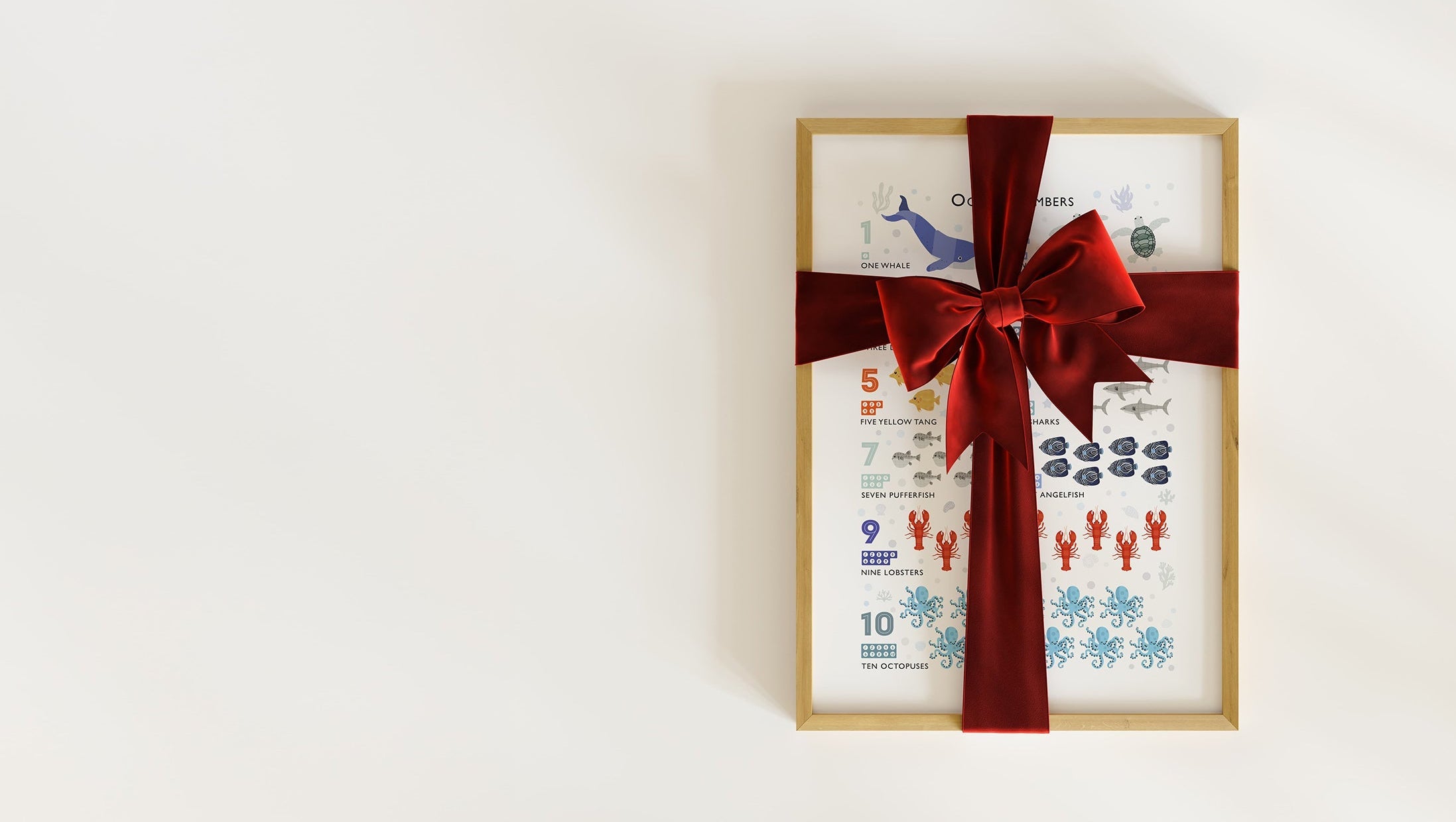 A framed art print featuring an ocean themed counting poster, wrapped in a festive red velvet ribbon for Christmas.