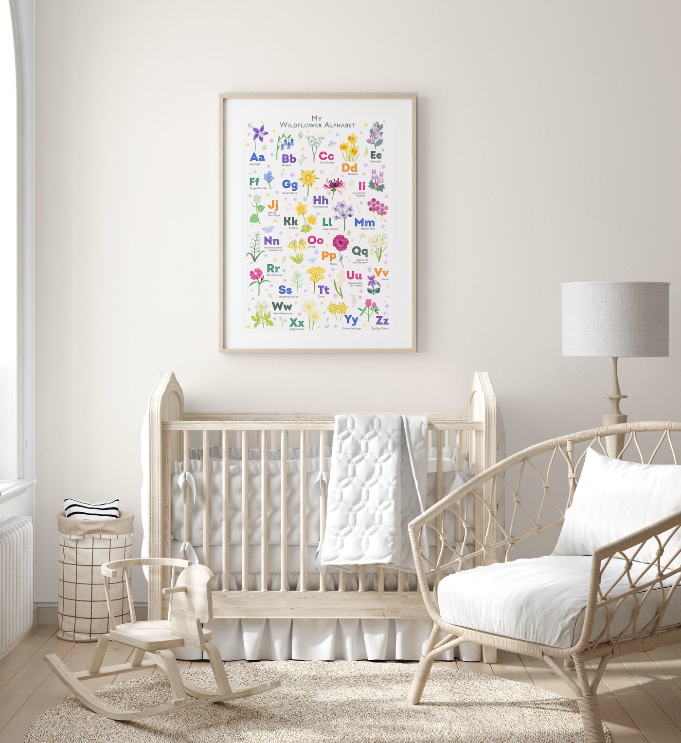 Image of a framed personalized wildflower alphabet print hanging on a light colored wall above a crib