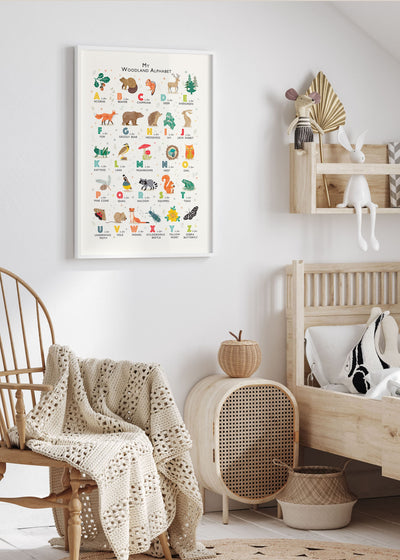 A large woodland alphabet print, framed in a white frame in a modern childs bedroom