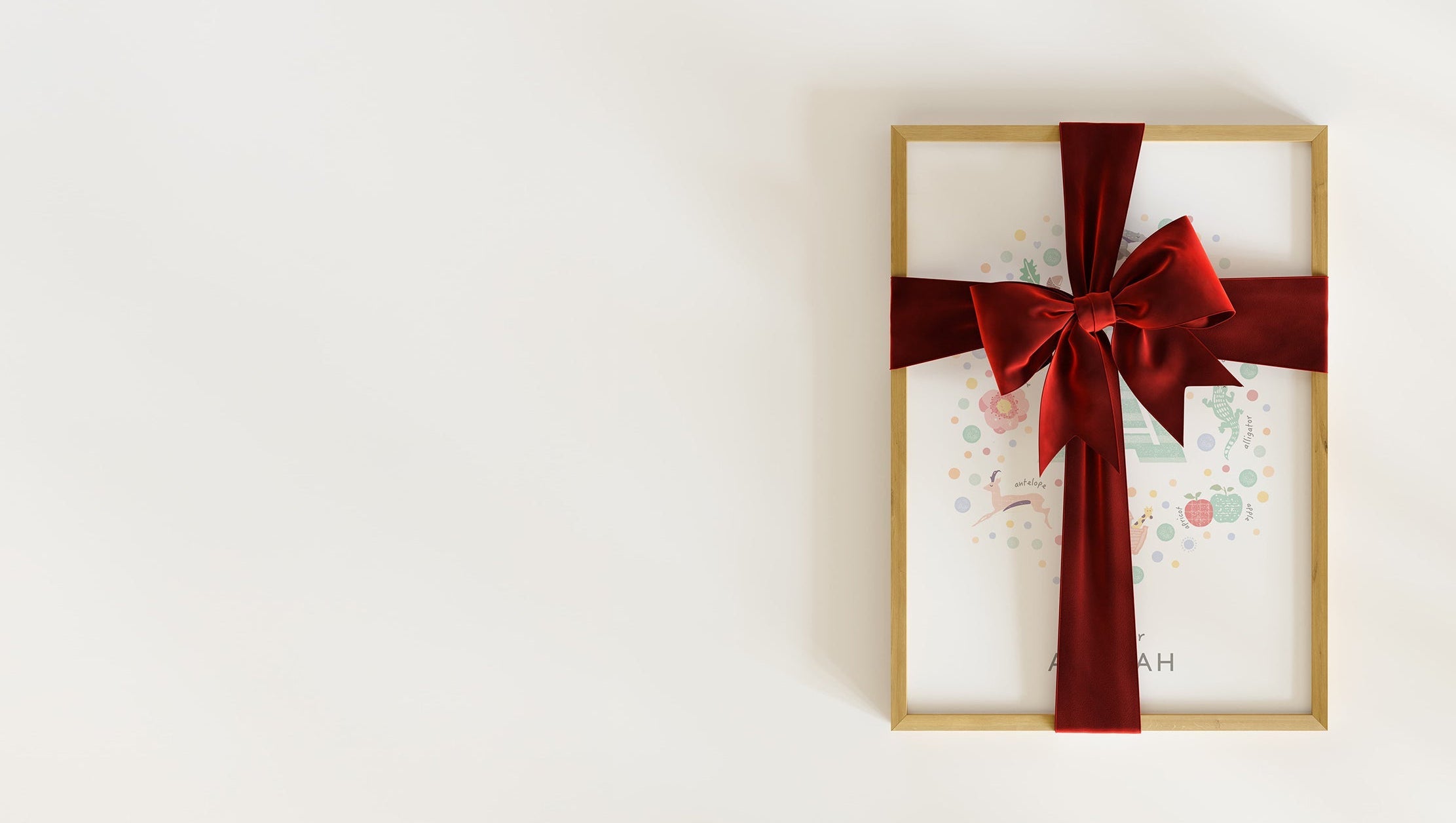 A framed, pastel-coloured personalised initial letter a print for a nursery, wrapped in a festive red velvet ribbon.