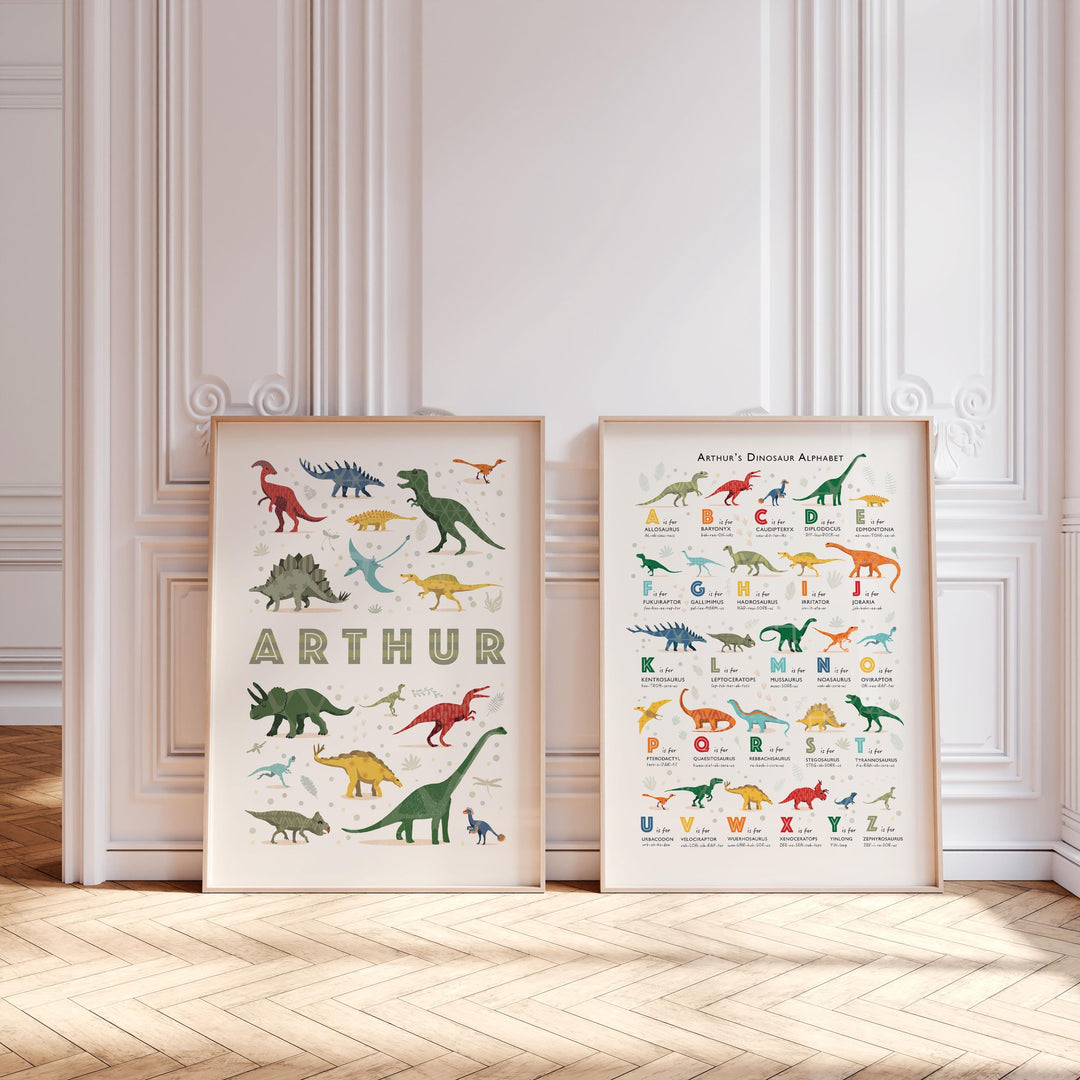 Pair of dinosaur alphabet prints in oak frames leaning against wall — modern nursery decor and personalised children’s gift idea.