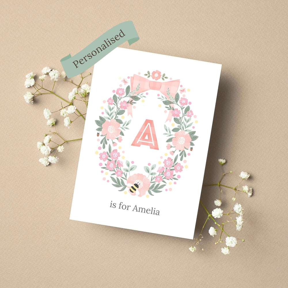 A personalised new baby card featuring a rustic wreath of hand-drawn botanicals and leaves, with the initial A  in the centre with the name Ameilia underneath.