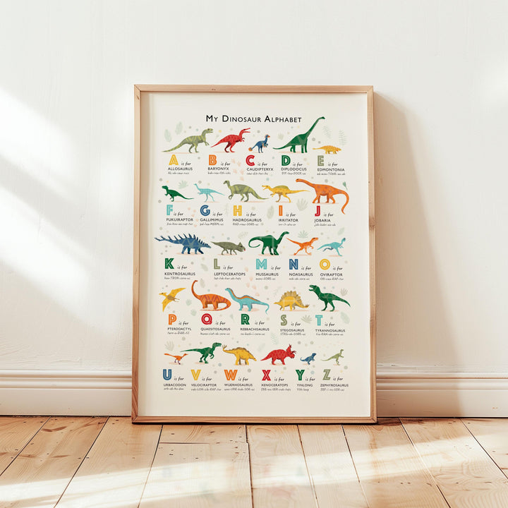 Dinosaur alphabet print displayed in light-filled nursery with oak frame and soft neutral tones — educational wall art for kids.