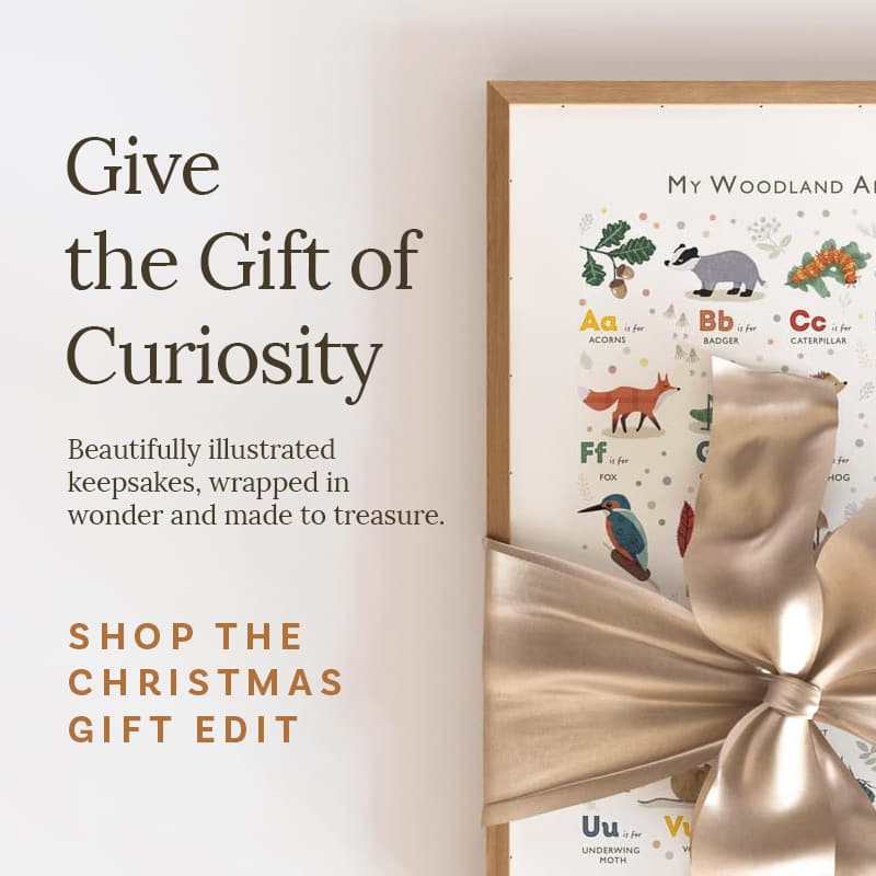 Framed children's alphabet poster with a gold bow, text about gift ideas on a light background