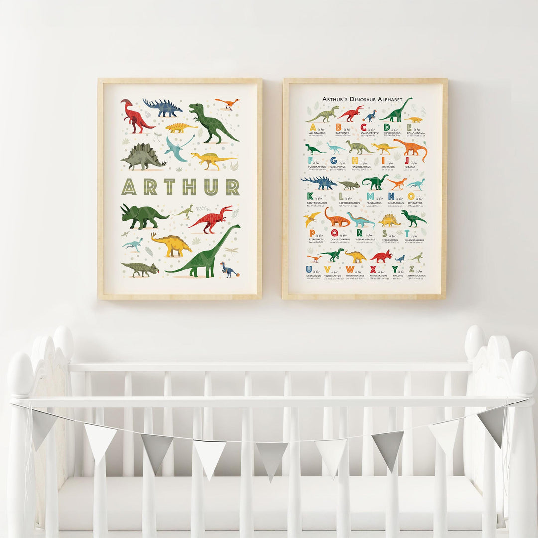 Framed personalised dinosaur alphabet and name prints hanging above a white crib in a modern nursery with neutral decor, featuring sustainable cotton rag paper and playful dinosaur illustrations.