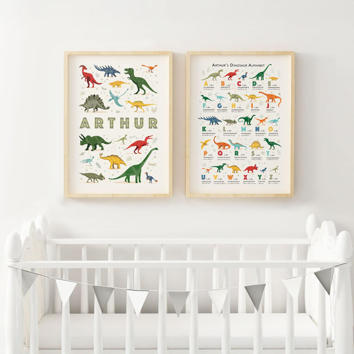 Framed personalised dinosaur alphabet and name prints hanging above a white crib in a modern nursery with neutral decor, featuring sustainable cotton rag paper and playful dinosaur illustrations.