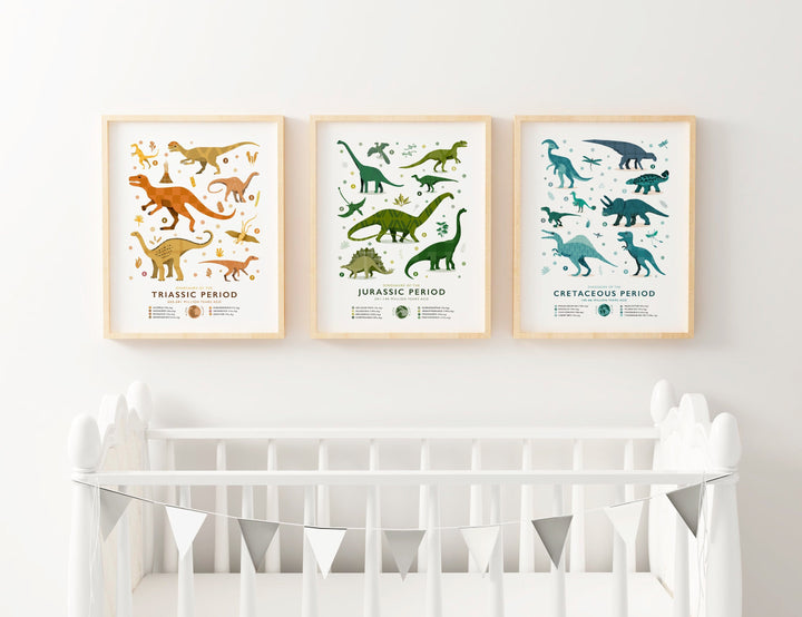 Set of three framed dinosaur era art prints displayed above a white crib. The prints showcase the Triassic, Jurassic, and Cretaceous periods, each with hand-illustrated dinosaurs in beautiful rich tones