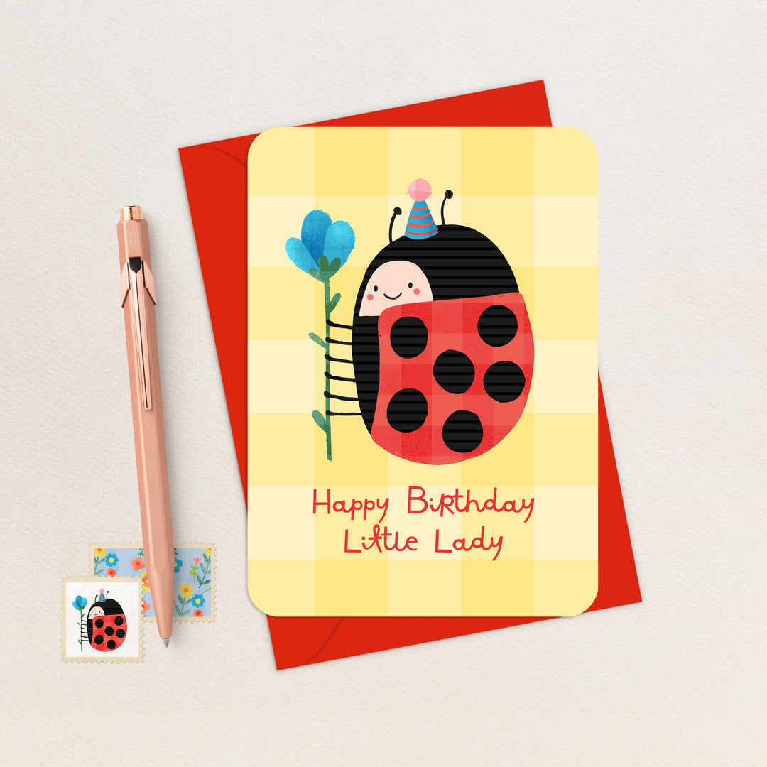 Birthday card with a ladybug design and a pen on a light gray background