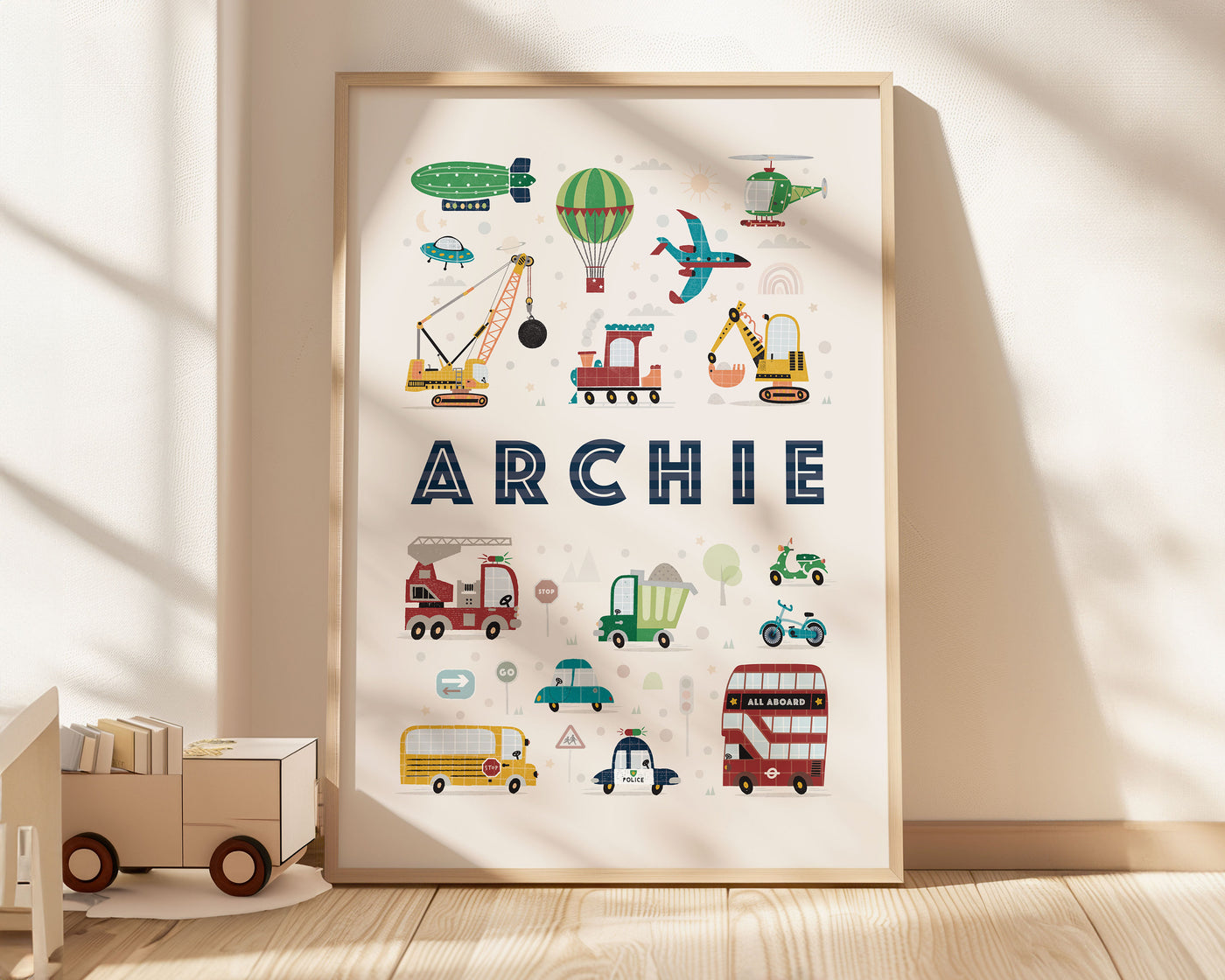 A warm, sunlit nursery room corner with a framed art print &#39;ARCHIE&#39; on the floor, next to a wooden toy truck, showcasing PaperPaintPixels&#39; personalized design.