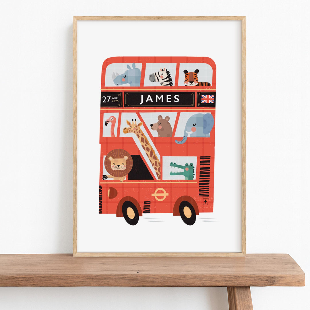Personalised London Bus wall art in a natural wooden frame, sitting on a nursery wooden bench, featuring cute zoo animals like a lion, giraffe, and elephant. The custom name print also displays a birth date and flag of your choice.