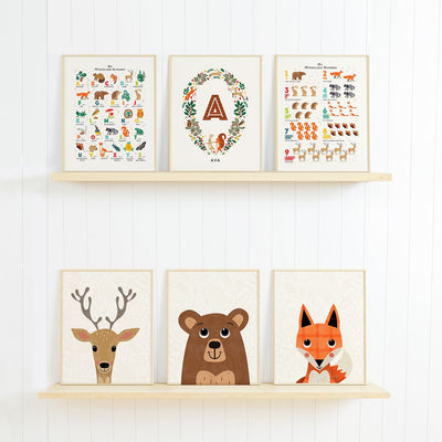 Two shelves displaying a charming collection of woodland-themed nursery art prints, featuring illustrated animals like a deer, bear, fox, and a personalized alphabet poster. Perfect for nature-inspired decor.