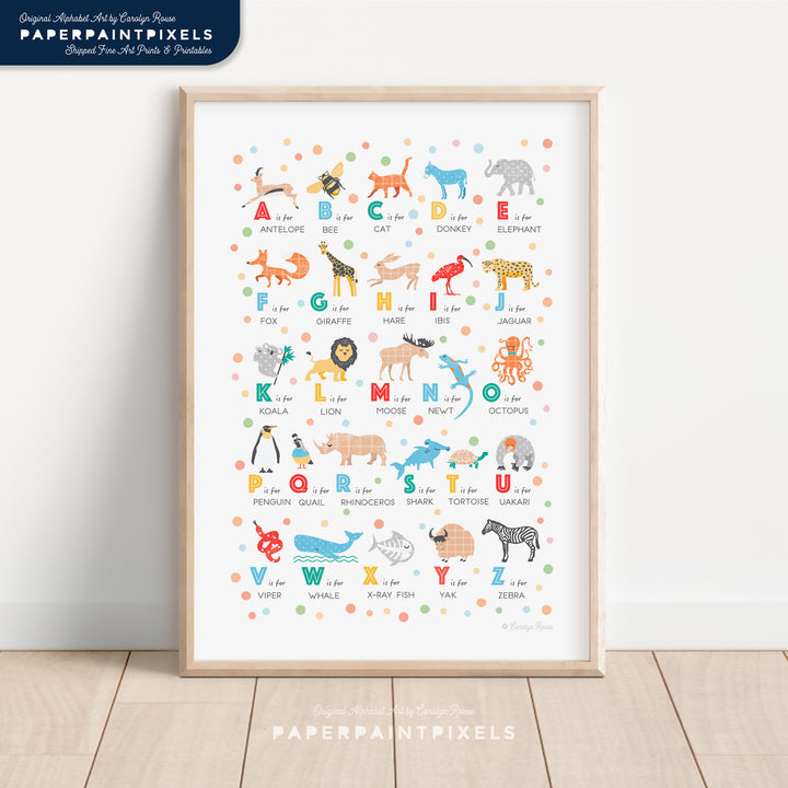 A printable animal alphabet poster with a clean, modern illustration style, shown framed on the wall of a contemporary child's nursery