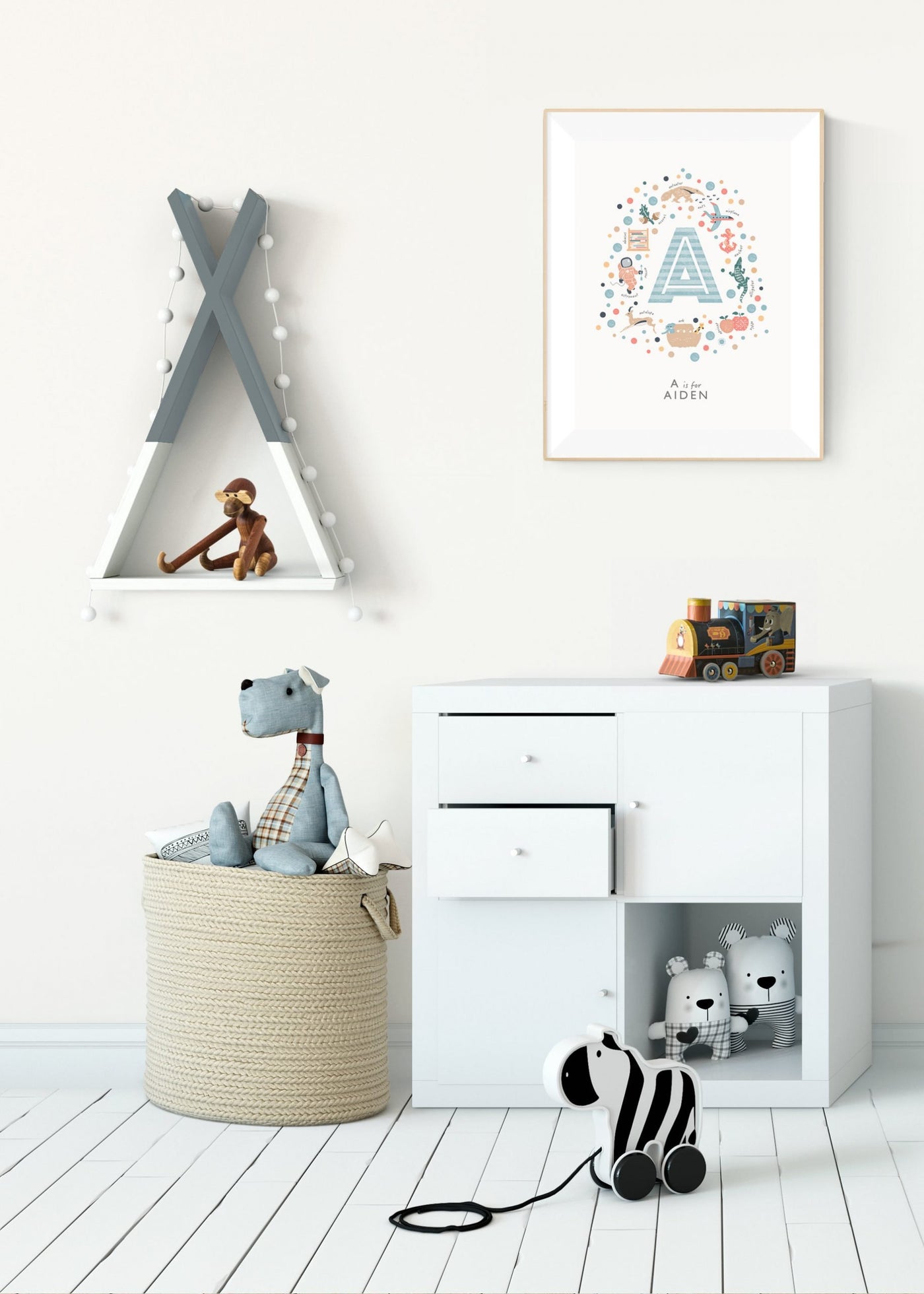 boys initial letter print - letter a  framed in a nursery wall about a small chest of drawers containing toys.